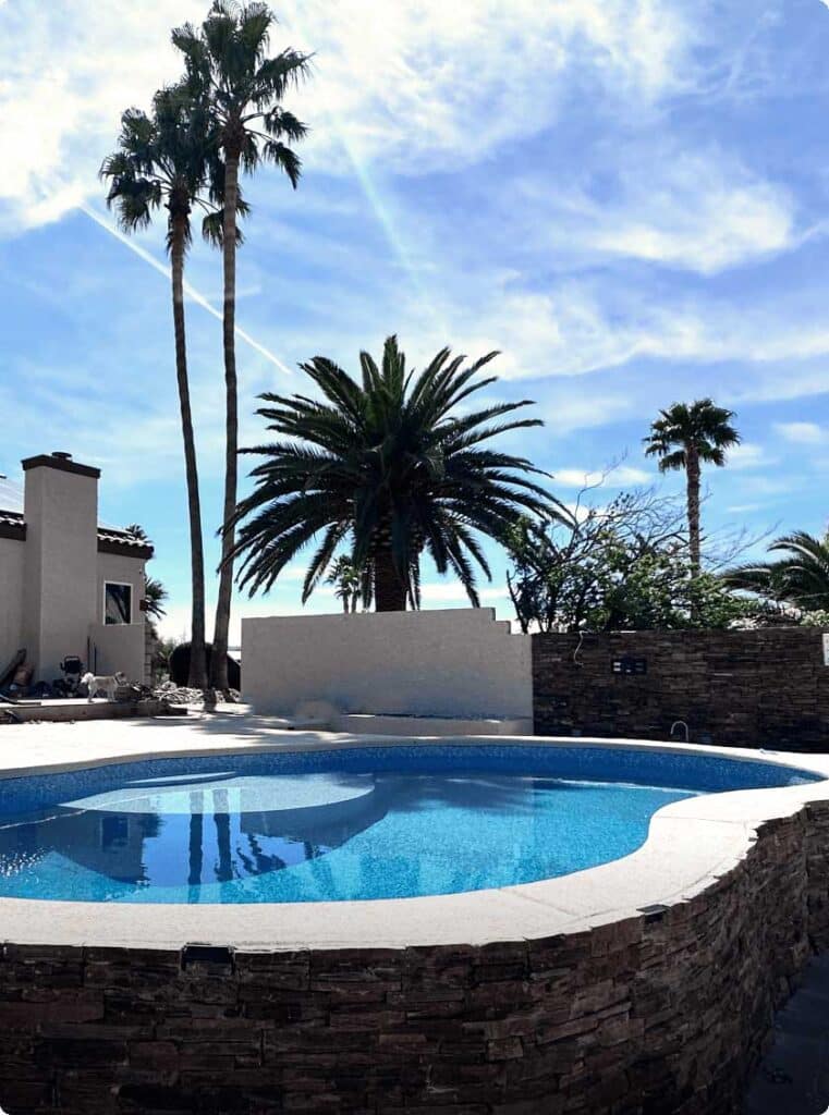 Vinyl spa and pool with stone coping and light-colored decking.