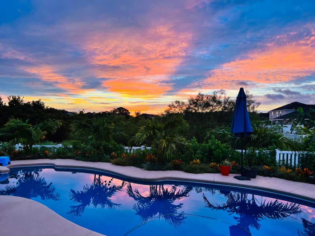 Fiberglass pool in a Fort Lauderdale backyard at sunset with vivid sky and lush landscaping